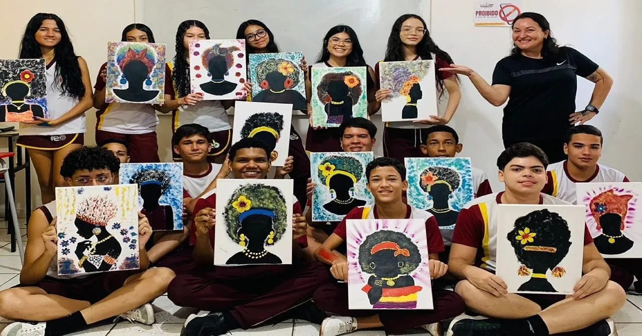 Turma de estudantes no chão segurando telas com silhuetas de mulheres de cabelos floridos.